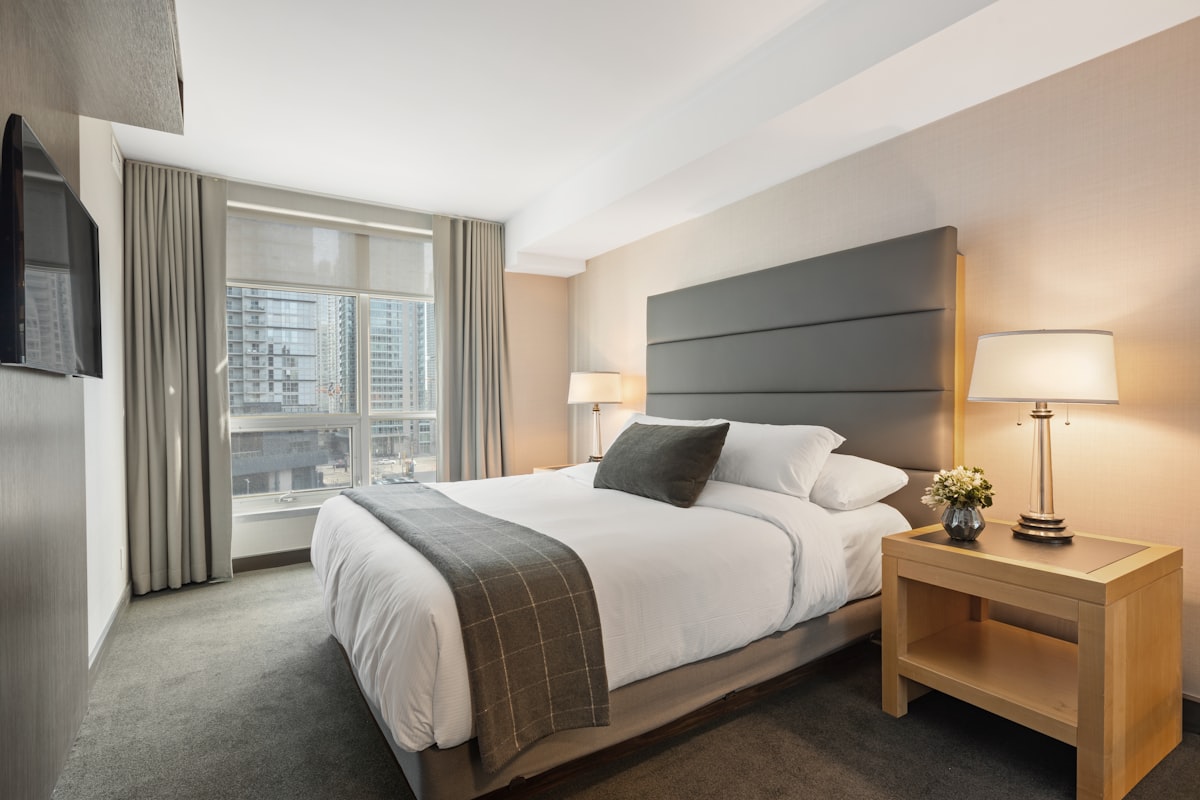 Neatly made hotel bed with white pillows in a quiet, softly lit room